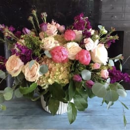 Mixed bouquet of pink and cream flowers in a white vase