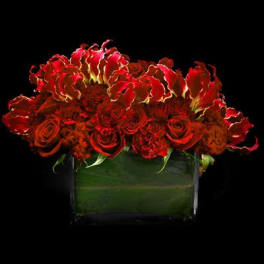Red roses and red tropical flowers in a square glass vase