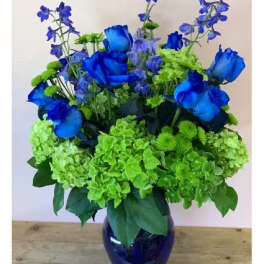 Blue roses and green hydrangeas in a dark glass vase