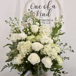 White roses and hydrangeas arranged in a white vase with greenery