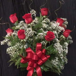 Red roses and baby's breath in a glass vase with a red bow