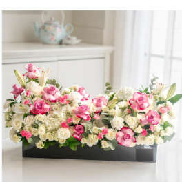 Pink and white floral arrangement in a black rectangular box