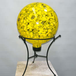 Yellow glass orb on a black metal stand