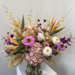 Mixed bouquet in a clear glass vase with pink, white, purple, and orange blooms
