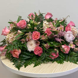 Pink roses and mixed blooms arranged low on a round table