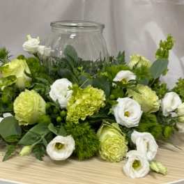 Low floral centerpiece with white and pale green blooms in a glass jar