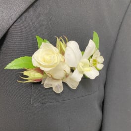 White boutonniere with rose and orchid on a dark suit lapel