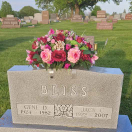 Pink and red floral arrangement on a gravestone in a cemetery