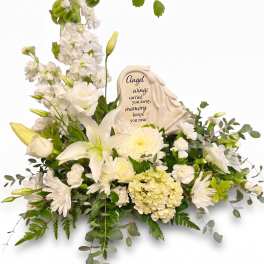 White sympathy floral arrangement with a memorial plaque and angel wings