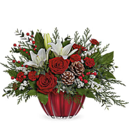 Red roses and white lilies in a red vase with pinecones and berries