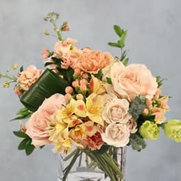 Peach and cream bouquet in a clear square vase