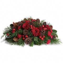 Low holiday centerpiece with red roses, pinecones, and evergreen accents
