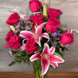 Pink roses and lilies arranged in a clear glass vase