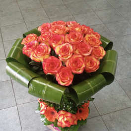 Bouquet of orange and pink roses with green wrap and orange gerberas