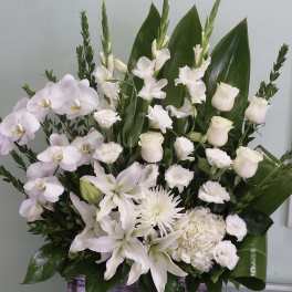 White floral arrangement with orchids, roses, lilies, and a chrysanthemum