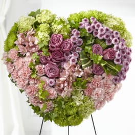 Heart-shaped floral arrangement with pink roses, carnations, and green hydrangeas