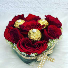 Red roses arranged with gold-wrapped chocolates in a round box