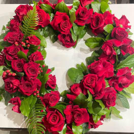 Heart-shaped arrangement of red roses with green foliage