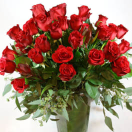 Red roses arranged in a clear glass vase