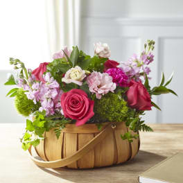 Pink and red roses with mixed blooms in a wooden basket