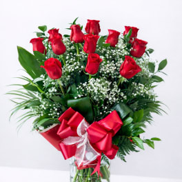 Red roses arranged in a clear glass vase with a red ribbon bow