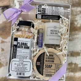 Gift box with floral-scented bath and soap items tied with lavender ribbon
