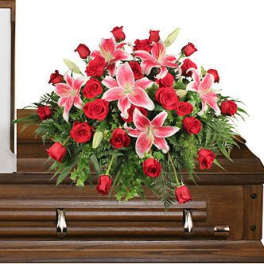 Red roses and pink lilies arranged on a wooden casket