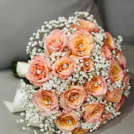 Peach roses with baby's breath in a rounded bouquet