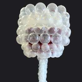 Clear balloon sculpture shaped like a tree on a black background