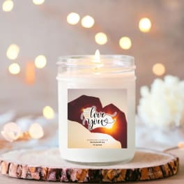 White jar candle with a "love you" label on a wood slice