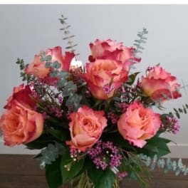 Pink and peach roses in a clear glass vase with eucalyptus