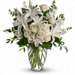 White lilies and roses arranged in a clear glass vase