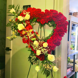 Heart-shaped floral standing arrangement with red carnations and yellow roses