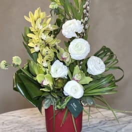 Tall floral arrangement with white blooms and yellow orchids in a red vase