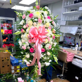 Large pink and white floral standing spray with a pink bow