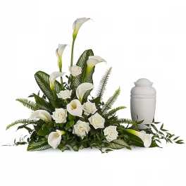 White calla lilies and roses arranged beside a white urn