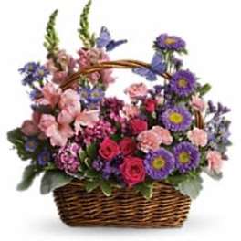 Mixed basket of pink, purple and blue flowers with decorative butterflies in a brown wicker basket
