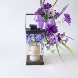 Purple floral arrangement in a lantern-style candle holder