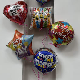 Cluster of colorful birthday balloons against a wall
