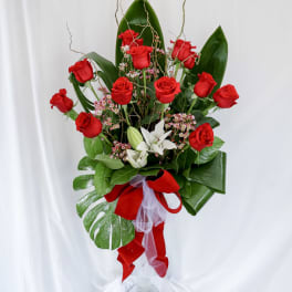 Tall bouquet of red roses with white flowers in a glass vase