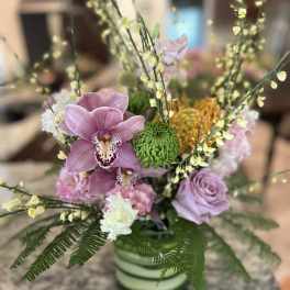 Pink orchids and roses in a striped vase with green accents