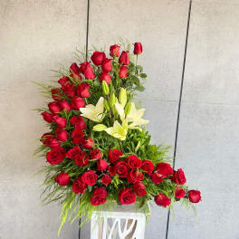 Large red rose and white lily arrangement in a white pedestal vase