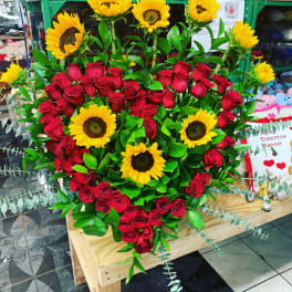 Heart-shaped bouquet of red roses and sunflowers on a wooden stand
