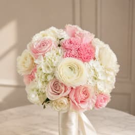 Pink and white bridal bouquet with roses, hydrangeas, and ranunculus tied with satin ribbon