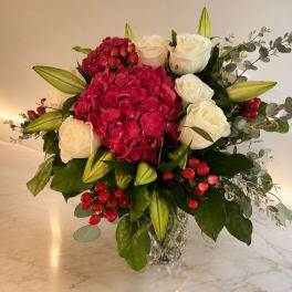 Bouquet of red hydrangea, white roses, and lily buds in a glass vase