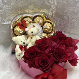 Red roses with teddy bears and chocolate candies in a heart-shaped box