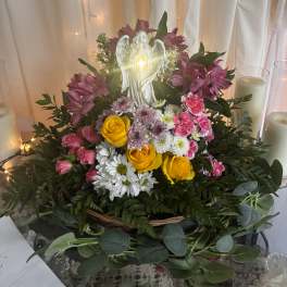 Mixed flower arrangement with roses, daisies, and an angel figurine