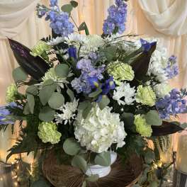 Large bouquet of white, blue, and green flowers in a white vase