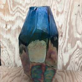 Blue iridescent geometric glass vase on a wooden surface