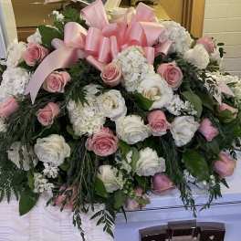 Pink and white rose casket spray with a large pink ribbon